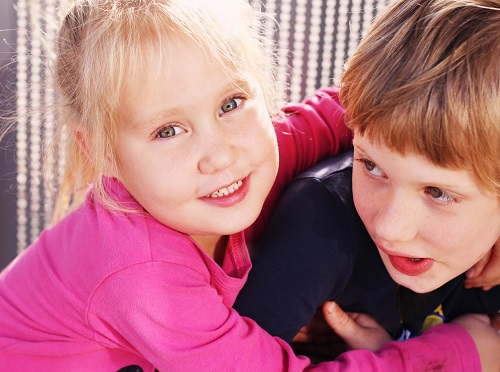 Portrait of happy girl with her autistic brother outdoors