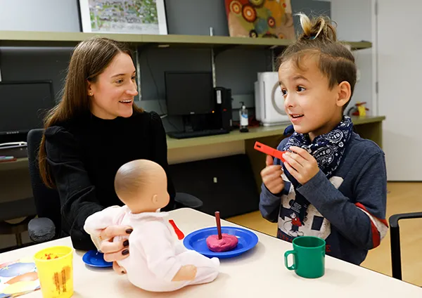 autism-evaluations-austism-clinic-northwestern child with autism playing with dolls and dishes northwestern neurodevelopmental diversity lab